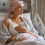 Frau nach Mastektomie im Krankenhausbett mit Verband und Kopftuch während der Genesung