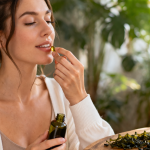 Frau nimmt Omega-3 Algenöl Kapsel in heller natürlicher Umgebung mit pflanzlichen Zutaten