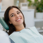 Frau sitzt entspannt im Zahnarztstuhl und lächelt – Symbol für Mundgesundheit und ihre Verbindung zur ganzheitlichen Gesundheit laut TCM