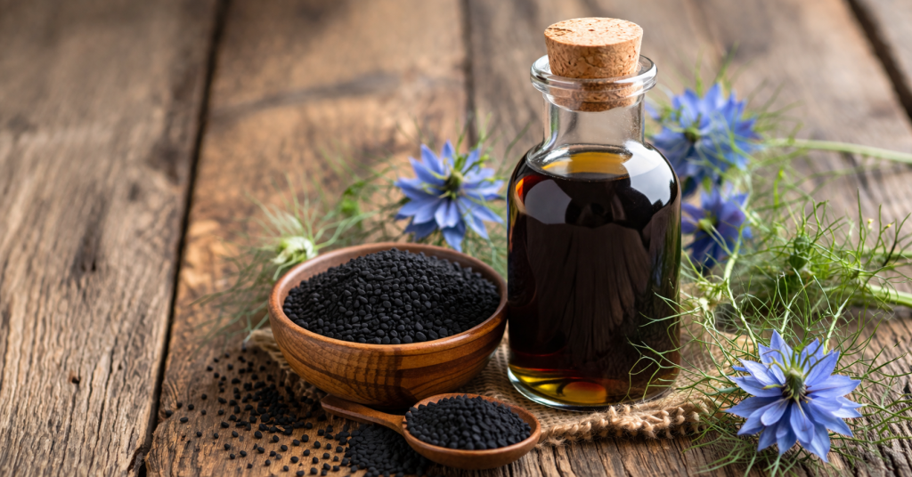 Schwarzkümmelöl in Glasflasche mit Schwarzkümmelsamen auf Holztisch, natürliche Darstellung