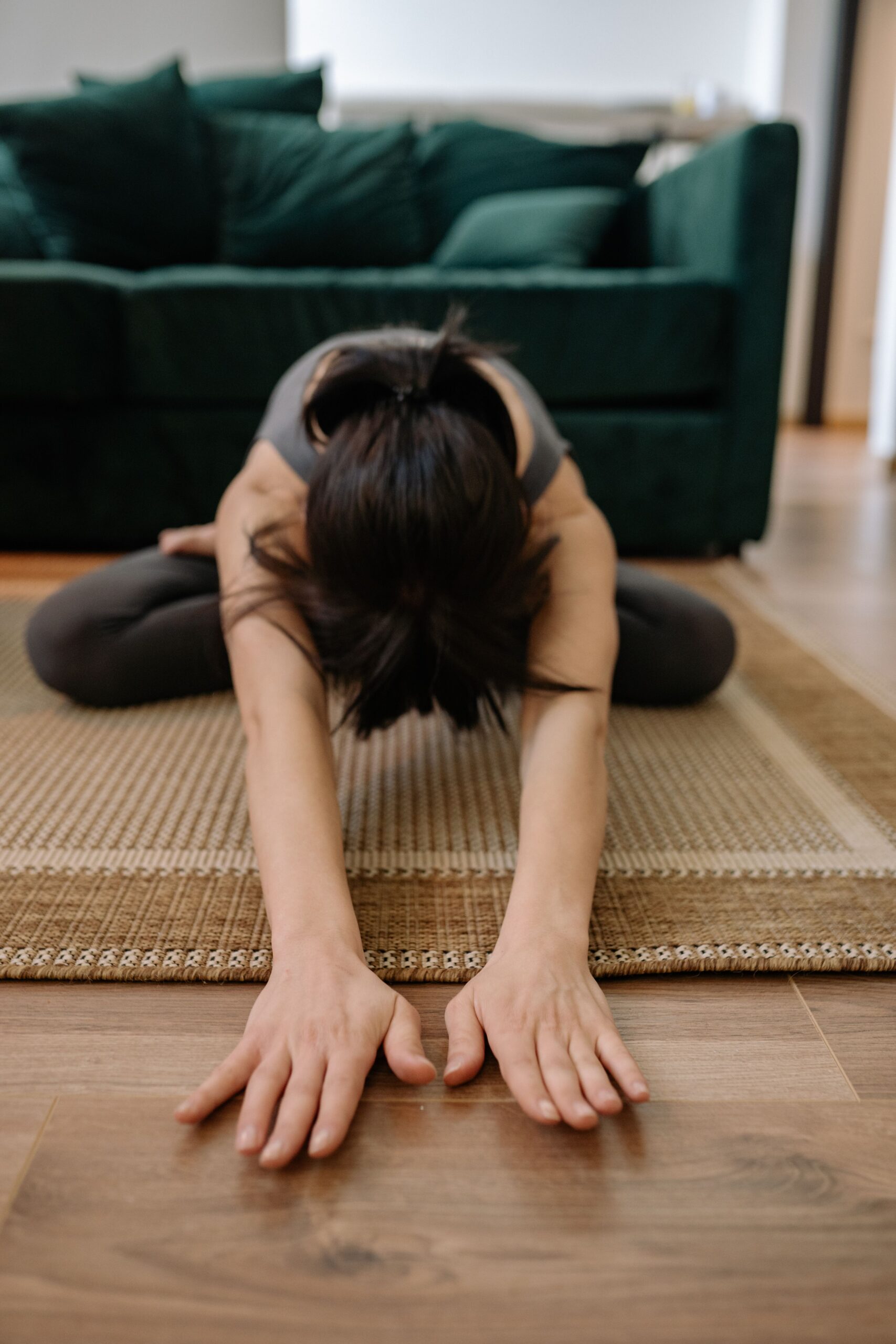 Frau macht eine entspannende Yoga-Dehnung auf einer Matte im Wohnzimmer, um Stress abzubauen und den Cortisolspiegel zu senken.