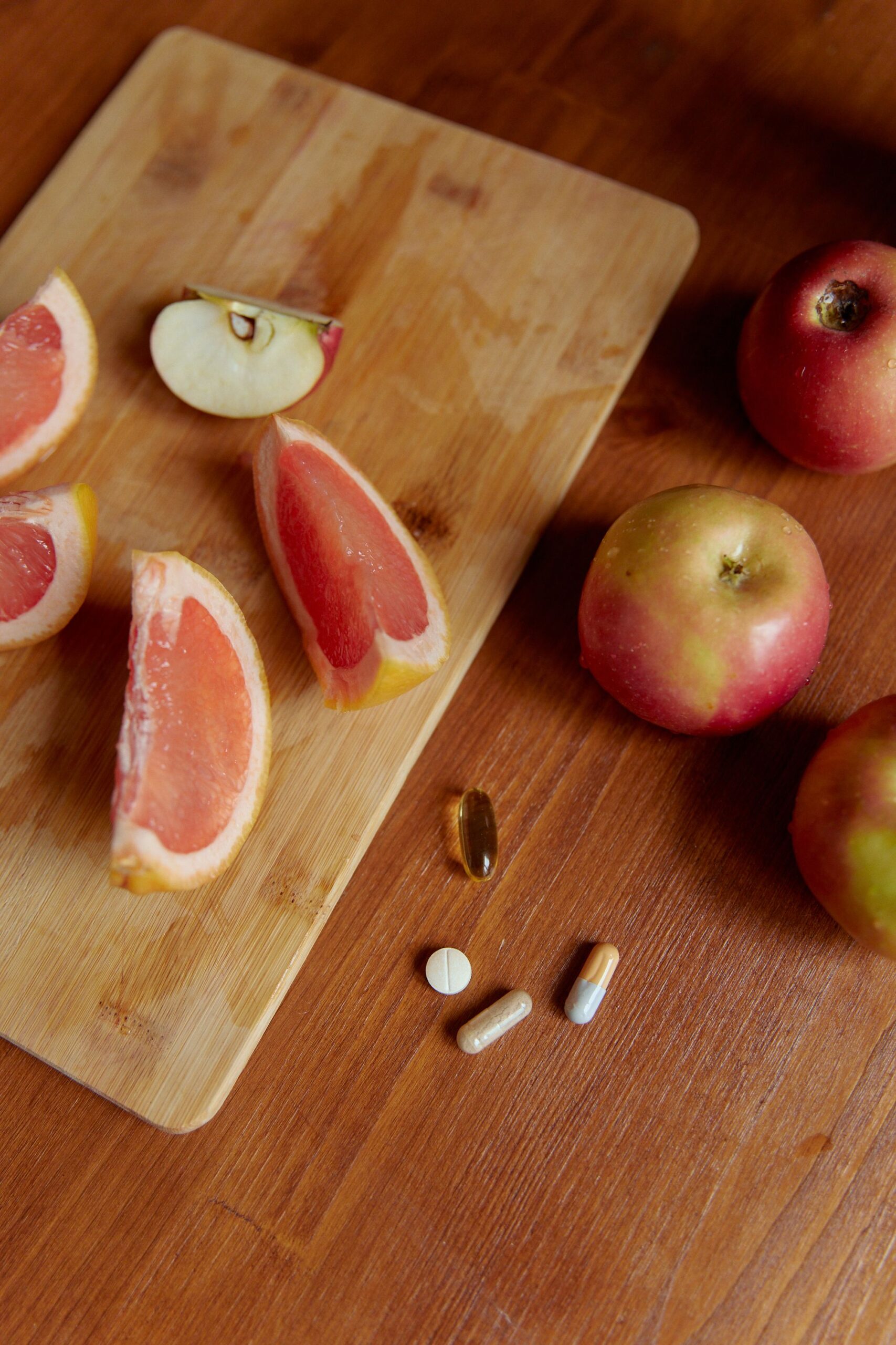 Frisches Obst mit Nahrungsergänzungsmitteln auf einem Holztisch als Symbol für eine nährstoffreiche Ernährung.