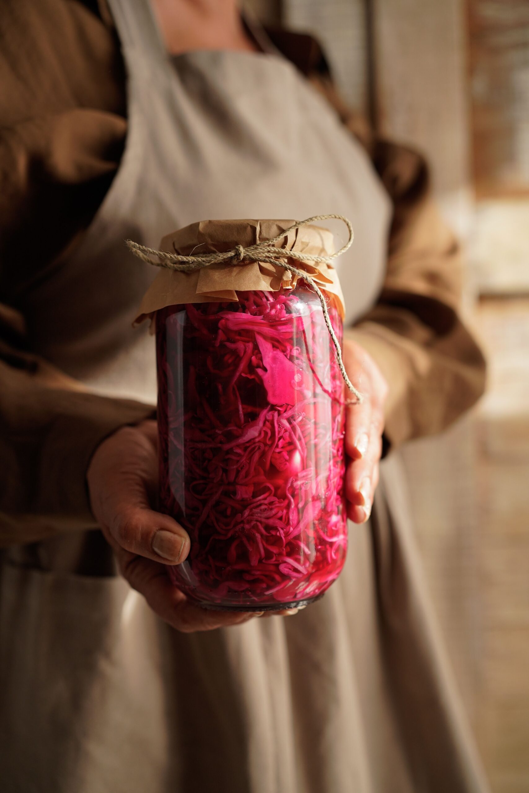 Frau hält ein Glas mit selbst fermentiertem Rotkohl in den Händen – probiotisches Lebensmittel zur Unterstützung der Darmgesundheit und des Mikrobioms.