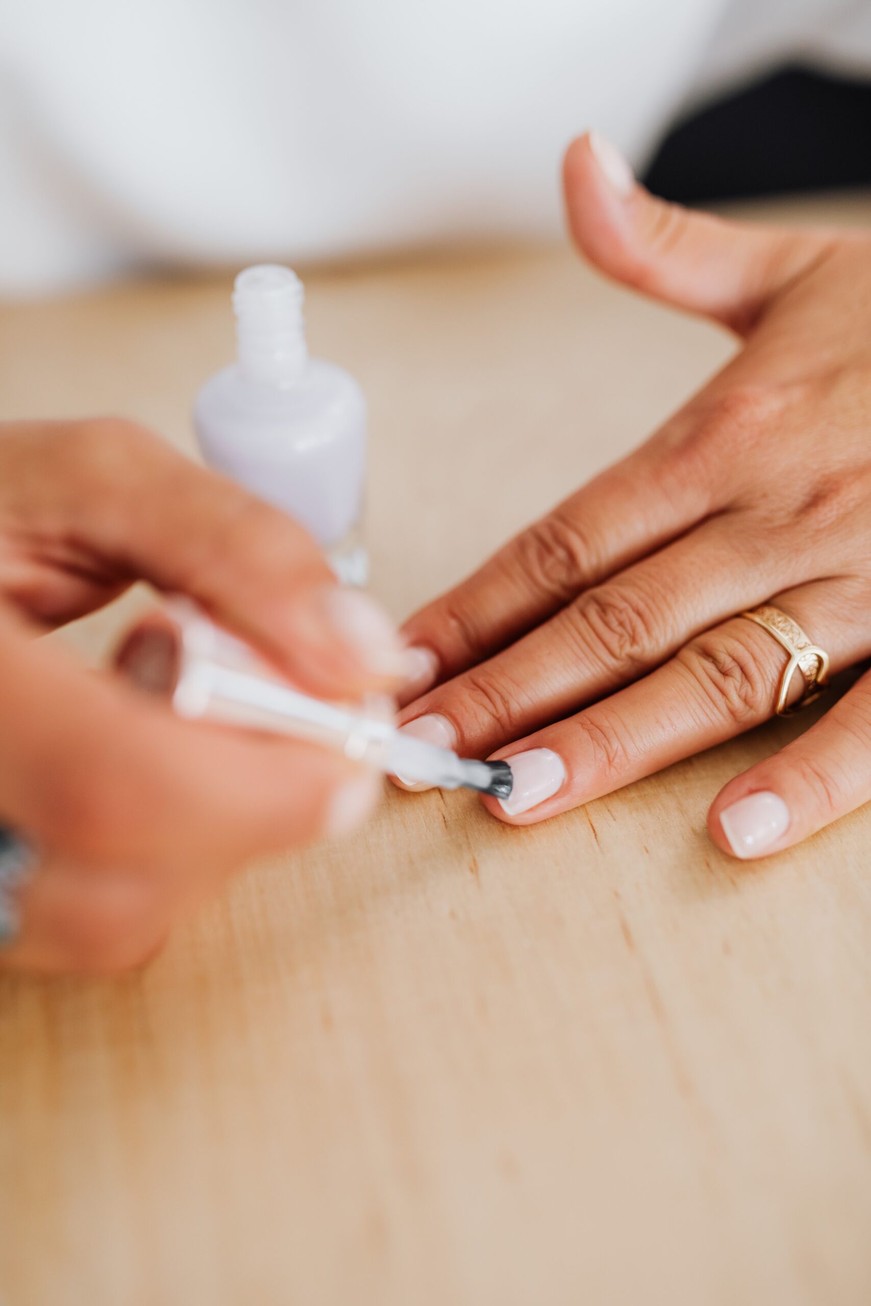 Natürliche Nagelpflege – transparenter Pflegelack wird auf gepflegte Fingernägel aufgetragen.