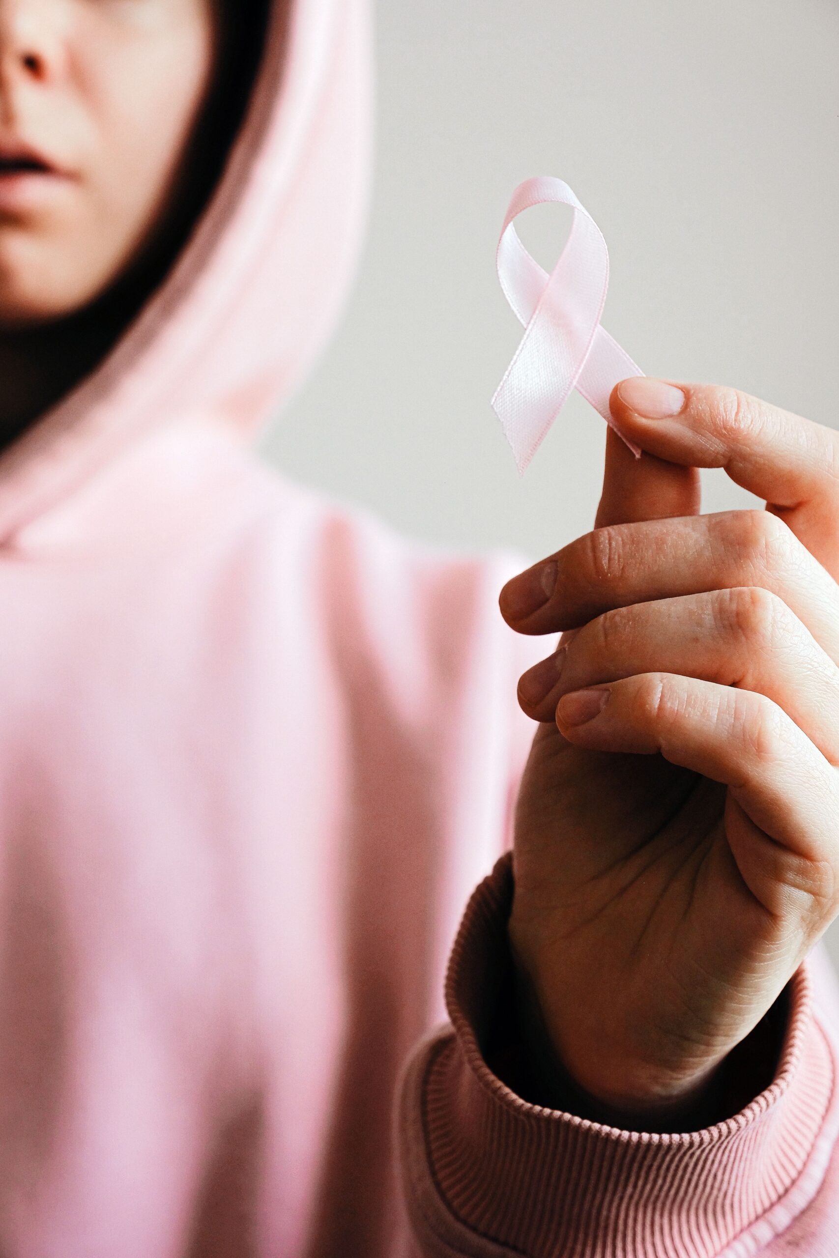 Person hält eine rosa Schleife als Symbol für Brustkrebs, Hoffnung und Solidarität in der Hand